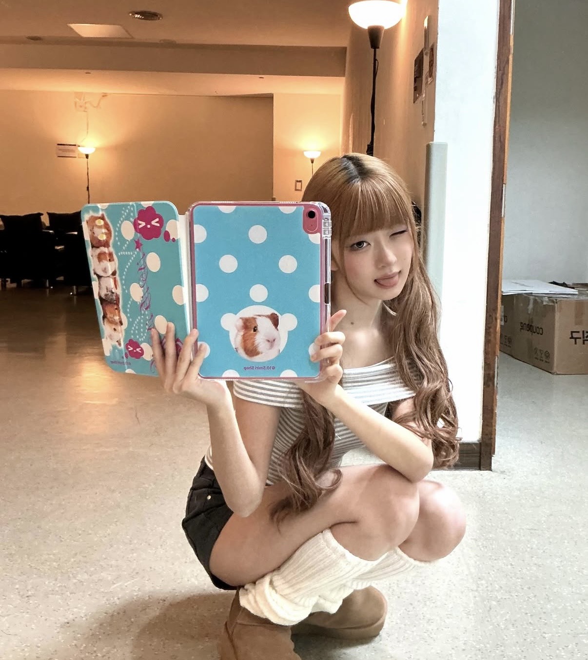 IVEのレイがiPadを持っている写真。水色でドットがらのハムスターが載っているカバーをつけている。